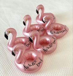 six pink flamingos with names on them sitting on a white sheet in the shape of balloons