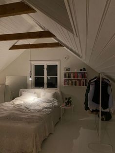 an attic bedroom with white walls and exposed ceilinging, bed is in the foreground