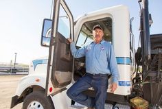 a man standing in the driver's seat of a semi truck