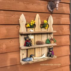 a wooden shelf with three shelves filled with figurines and flowers on top of it