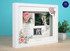 a wedding photo frame with flowers and photos on the front is sitting on a table next to a potted plant