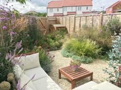 a garden with lots of plants and flowers in the back yard, along with a wooden bench