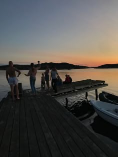 a group of people standing on top of a pier next to a body of water