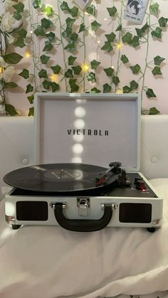 an old record player sitting on top of a bed next to a wall with ivy