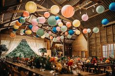 a large room filled with lots of tables covered in colorful paper lanterns hanging from the ceiling