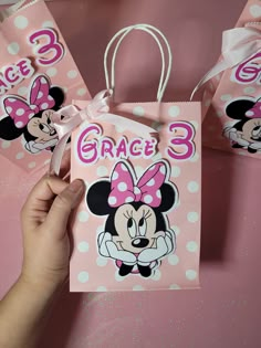 someone is holding up some pink minnie mouse gift bags with the name grace 3 on it