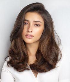 a woman with long brown hair is looking at the camera