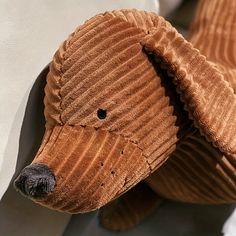 a close up of a dog made out of brown paper towels on a white wall