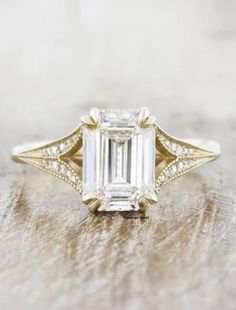 an emerald cut diamond ring on top of a wooden table