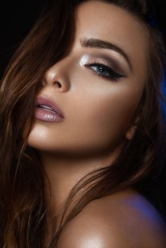 a woman with long brown hair and blue eyeshadow is posing for the camera