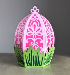 a pink and green paper easter egg sitting on top of a table