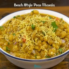 a bowl filled with beans and cheese on top of a wooden table next to a spoon