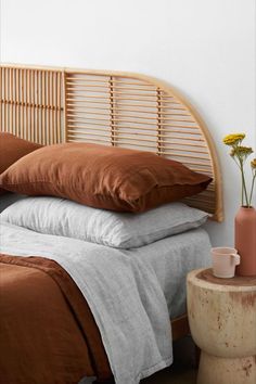 a bed with brown and white pillows on top of it next to a wooden headboard