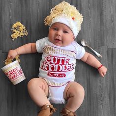 a baby is sitting on the floor with some food in it's hands and wearing a hat