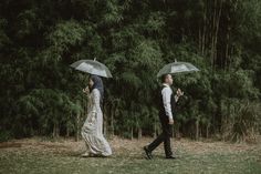 two people walking in the grass with umbrellas