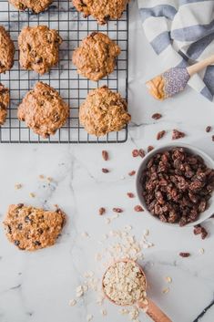 oatmeal cookies and raisins on a cooling rack next to a spoon