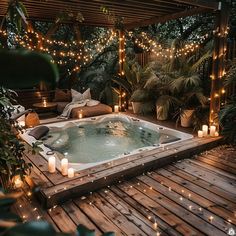 a hot tub surrounded by candles and greenery in the middle of a wooden deck