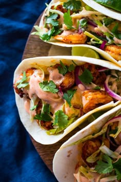 three tacos with chicken, lettuce and cilantro