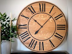 a large wooden clock sitting on top of a table next to a potted plant