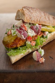 a sandwich with lettuce, tomato and other toppings on a cutting board