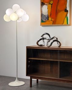 a lamp is sitting on top of a cabinet next to a painting and an art piece