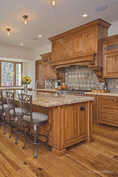 a large kitchen with wooden cabinets and marble counter tops, along with hardwood flooring