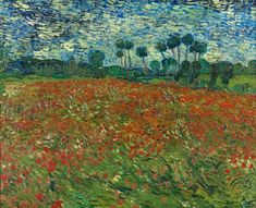 a field with red flowers and trees in the background