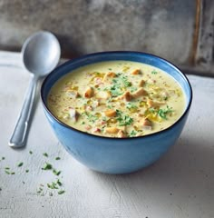 a blue bowl filled with soup next to a spoon