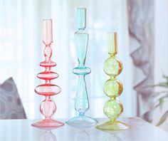 three glass candlesticks sitting on top of a table