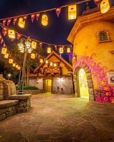 the lights are on in front of the house and lanterns strung from the roof above it