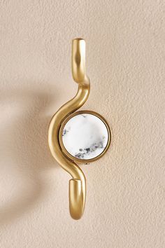 a mirror mounted to the side of a wall next to a beige wall with a gold frame