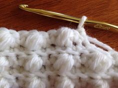 the crochet is being worked on with a golden knitting needle