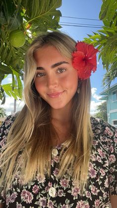 a woman with long blonde hair wearing a flower in her hair and smiling at the camera