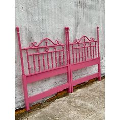 a pink metal headboard and foot board against a wall