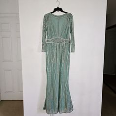 a green dress hanging on a wall next to a white door with a black hanger