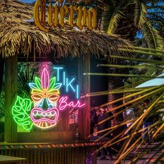 a tiki bar with neon signs and palm trees