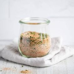 a glass jar filled with spices sitting on top of a white cloth