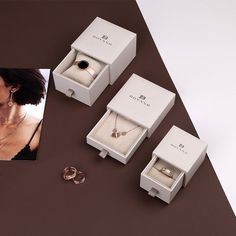 three rings and two necklaces on a table next to a box with an image of a woman