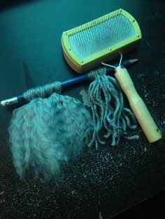 a pair of scissors and some hair sitting on a table next to a brush, comb and other items