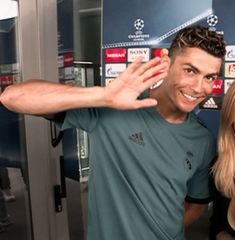 two people posing for a photo in front of a wall with soccer balls on it