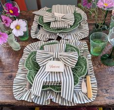 the table is set with plates, napkins and flowers