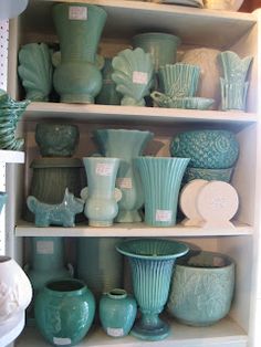 the shelves are filled with green vases and dishes