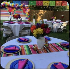 a table set up with colorful plates and napkins for an outdoor party or celebration