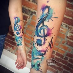 two people holding hands with colorful ink tattoos on their arms, both have musical notes painted on them