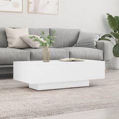 a white coffee table sitting on top of a rug in a living room next to a couch