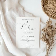 a white wedding card with the word just love on it next to some dried flowers