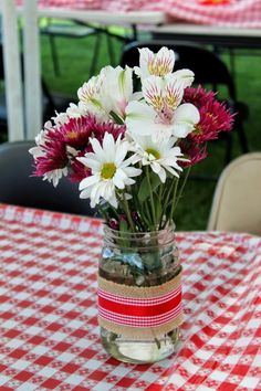 a vase filled with flowers sitting on top of a red and white checkered table cloth