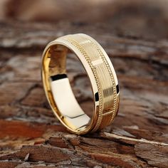 a gold wedding ring sitting on top of a rock