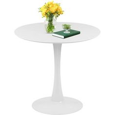 a white table with yellow flowers and a green book on the top that is sitting next to it