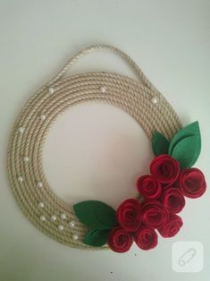 a rope wreath with red flowers and green leaves on white background, ready to be made into an ornament